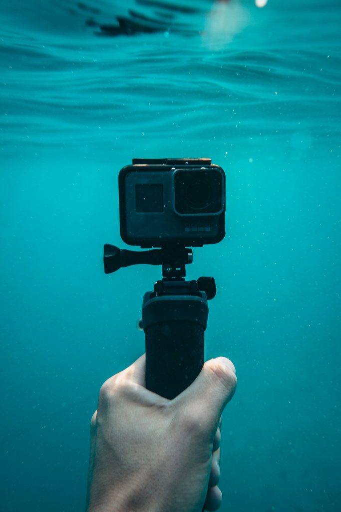 Action camera held underwater in clear blue water