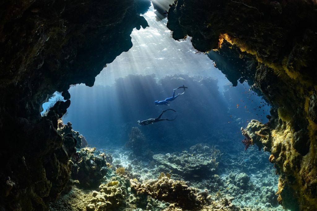 Trained cave diver swimming through an underwater cave passage