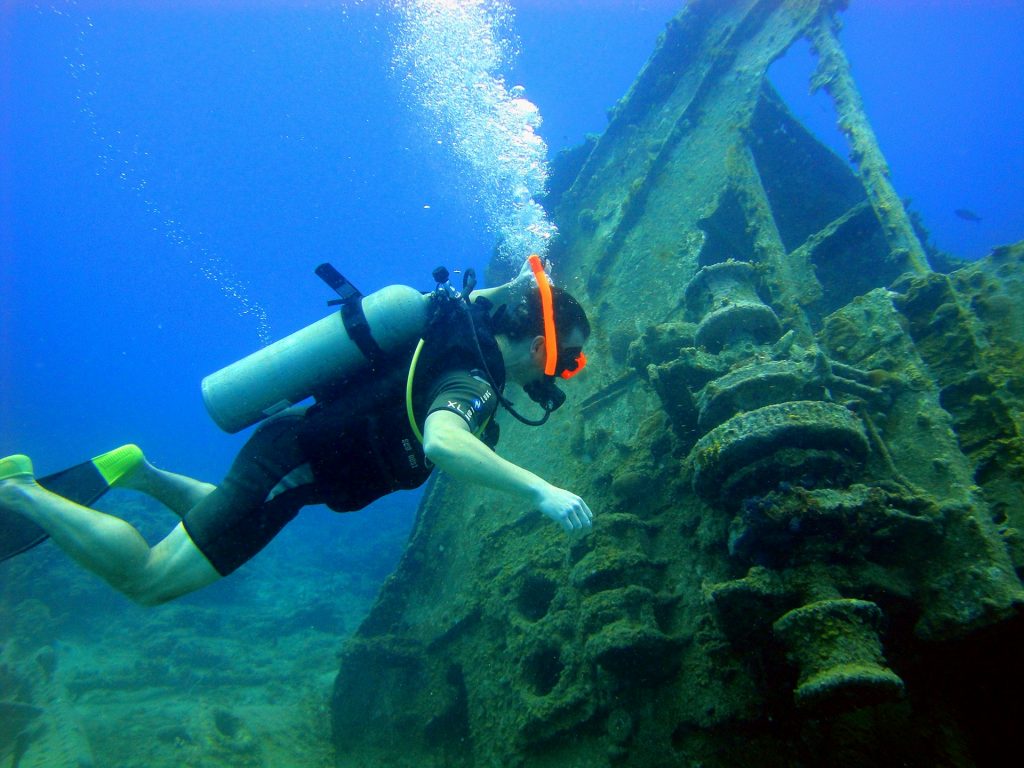Scuba diver hovering beside the hull of a sunken ship